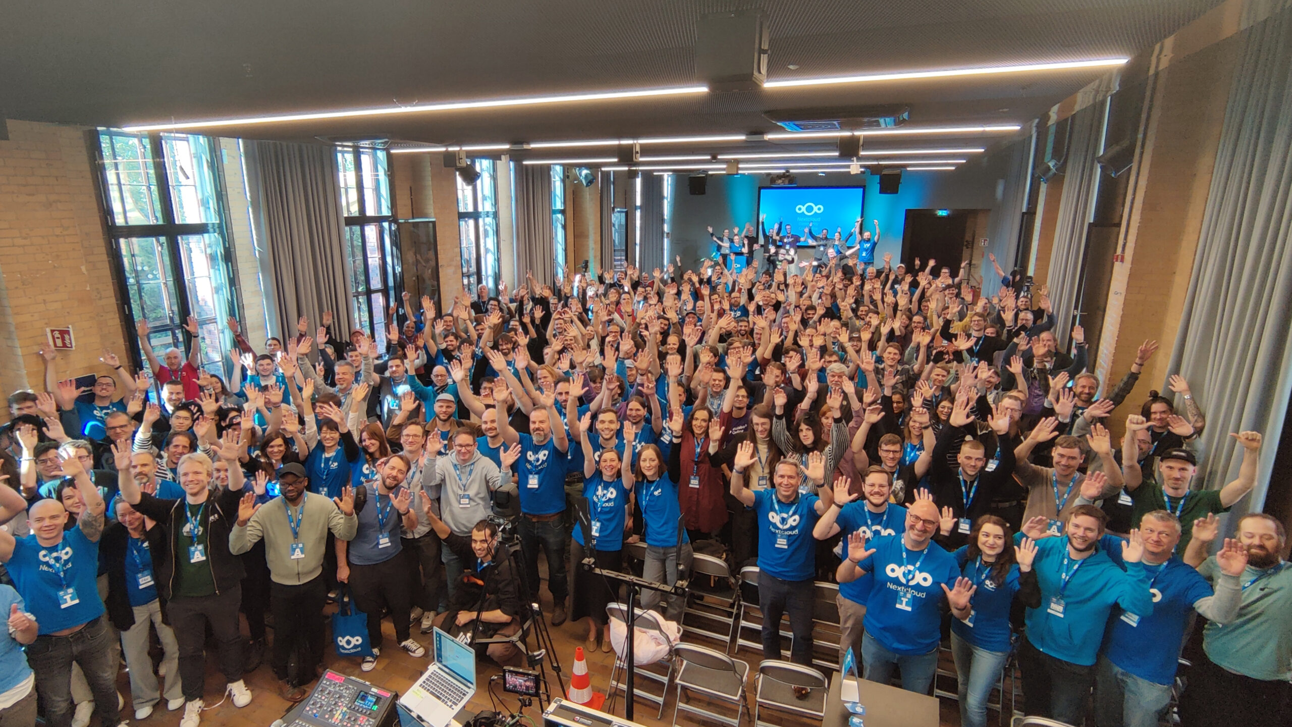 Group picture taken at the Nextcloud community at Community Conference in Berlin 2025, showing people smiling and waving at the camera.