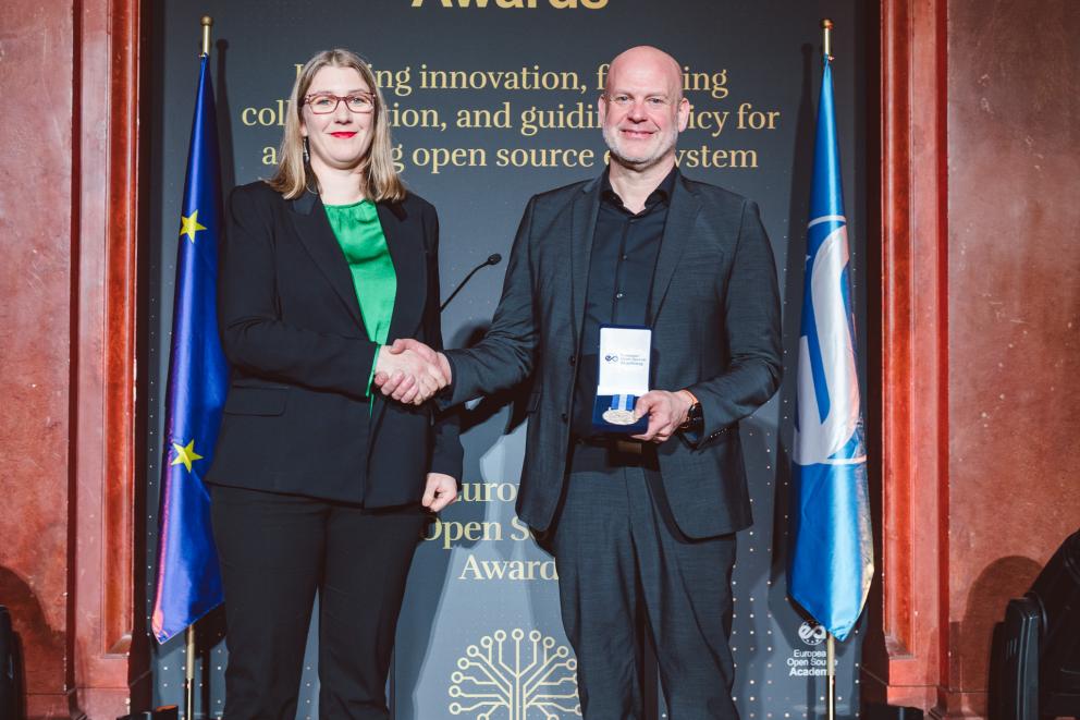 Photo taken at EOSA Awards 2026: Frank Karlitschek shakes hands with organizers when receiving his European Open Source Award for Business & Impact award